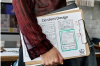 A person holding a clipboard with a document titled 'Content Design,' featuring diagrams and text related to wireframes or layout designs.