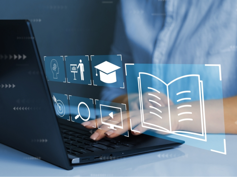 A person typing on a laptop with floating digital icons representing online learning, including symbols of a brain, instructor, graduation cap, and an open book.