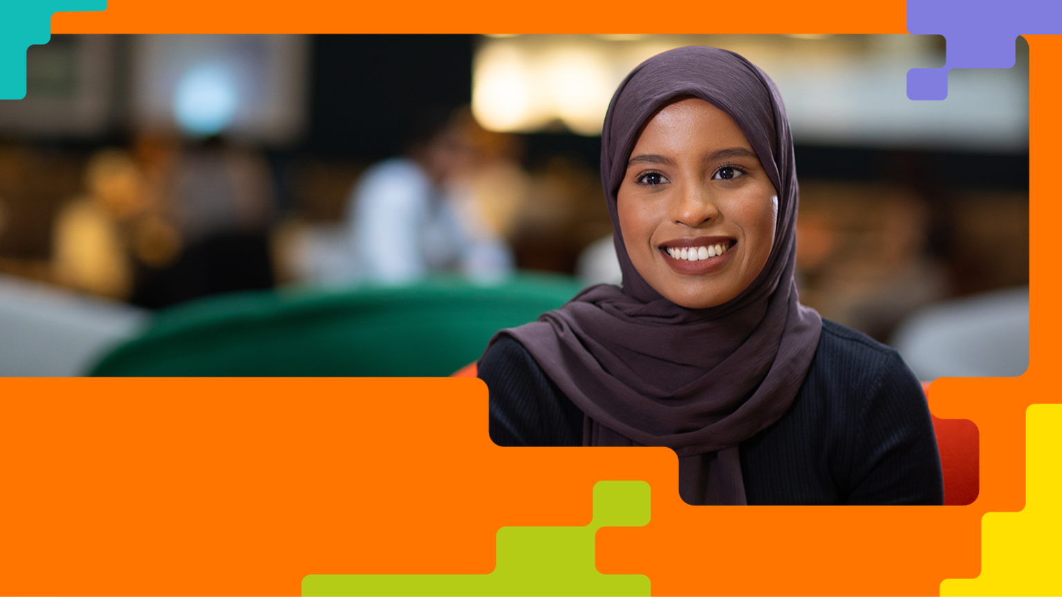 A woman wearing a headscarf and dark clothing smiles in an indoor setting with a blurred background. The image is framed by colourful geometric shapes, highlighting the individual in a professional or public environment.